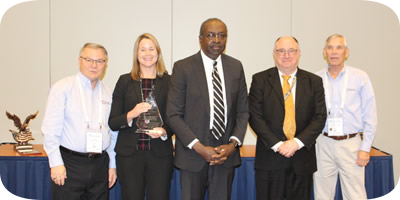 Photo of Director Kevin Jones, Deputy Director Erika Ragonese, and Instructional System Designer Stephen Fowler, accepting the FGDLA Award from FGDLA President Alex Autry and FGDLA Executive Director Jolly Holden.